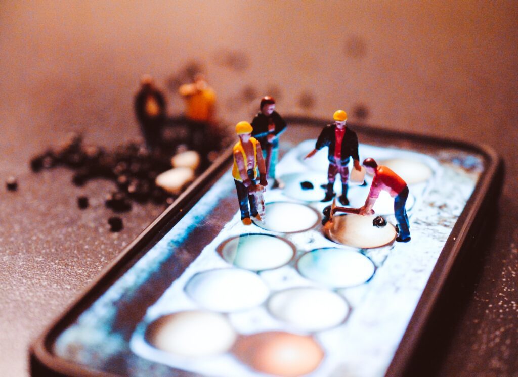 tiny model construction workers, working on a mobile phone screen