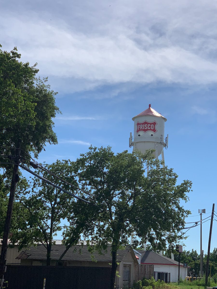 white and brown concrete tower near green trees under white clouds and blue sky during daytime