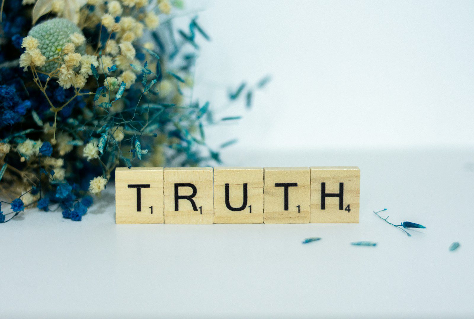 a wooden block spelling truth next to a bouquet of flowers